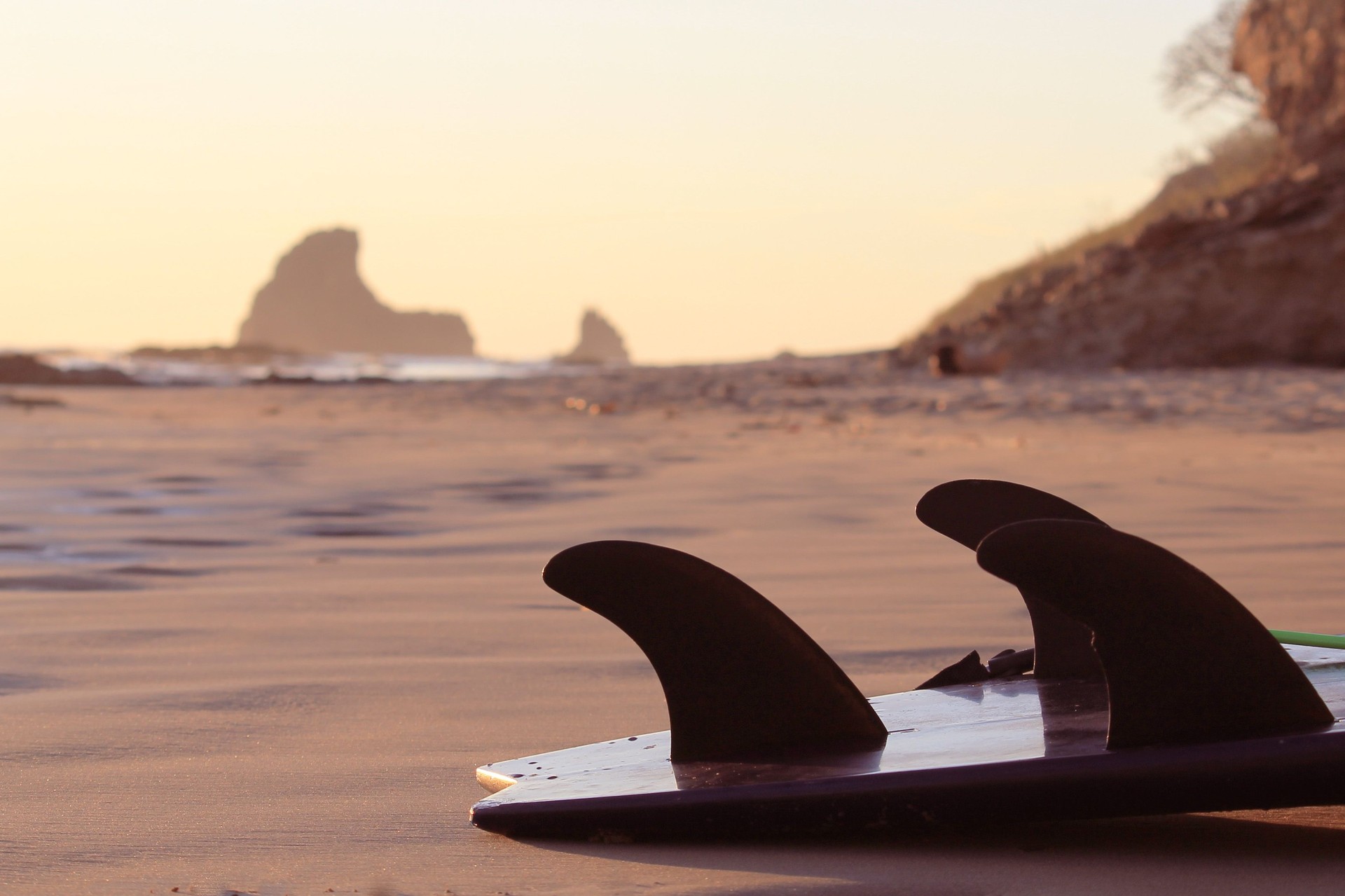 Surfboard lay on a empty beach at sunset